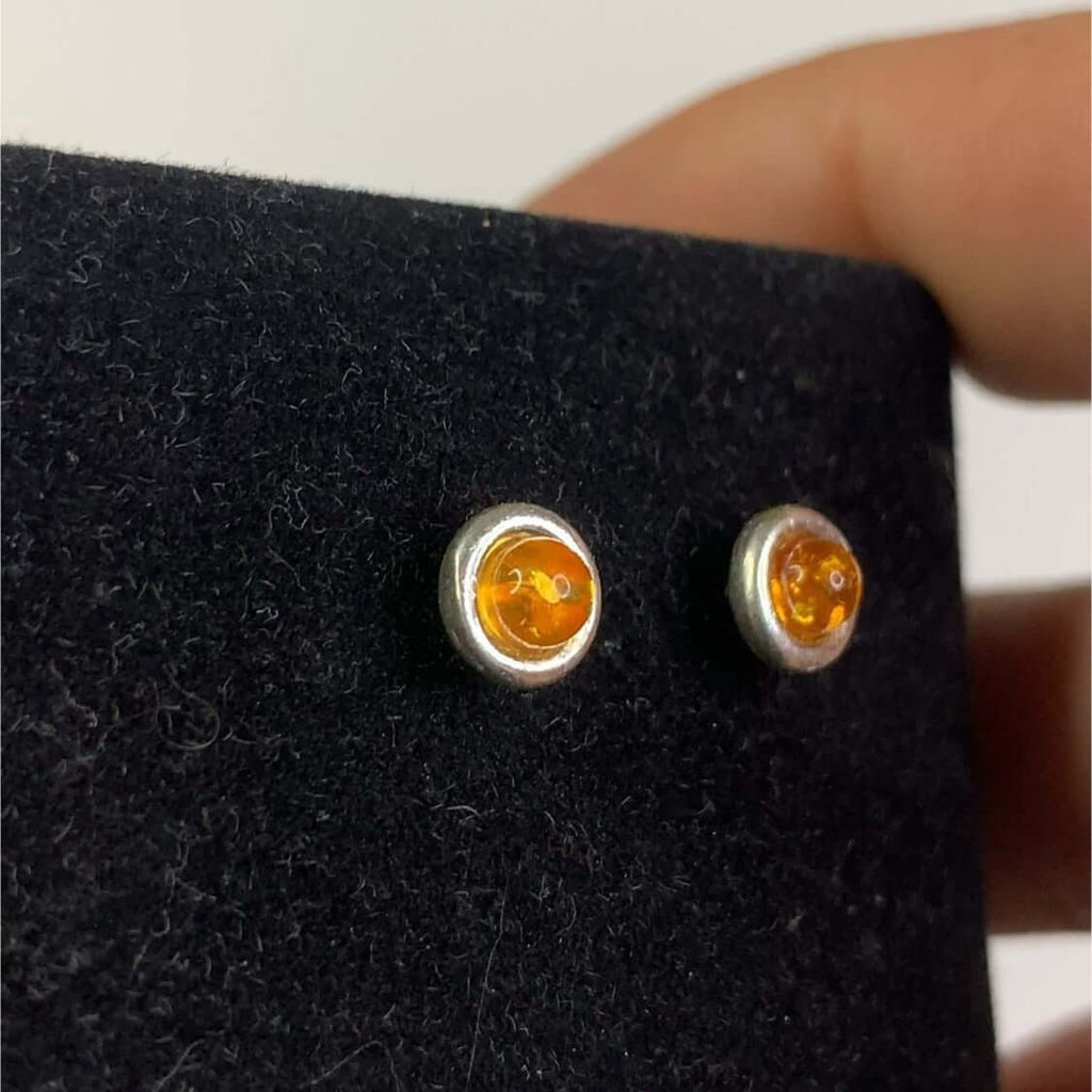 Sterling Silver 925 Women's Round Cognac Amber Stud Earrings with small round cut stones on black display card and hand holding.