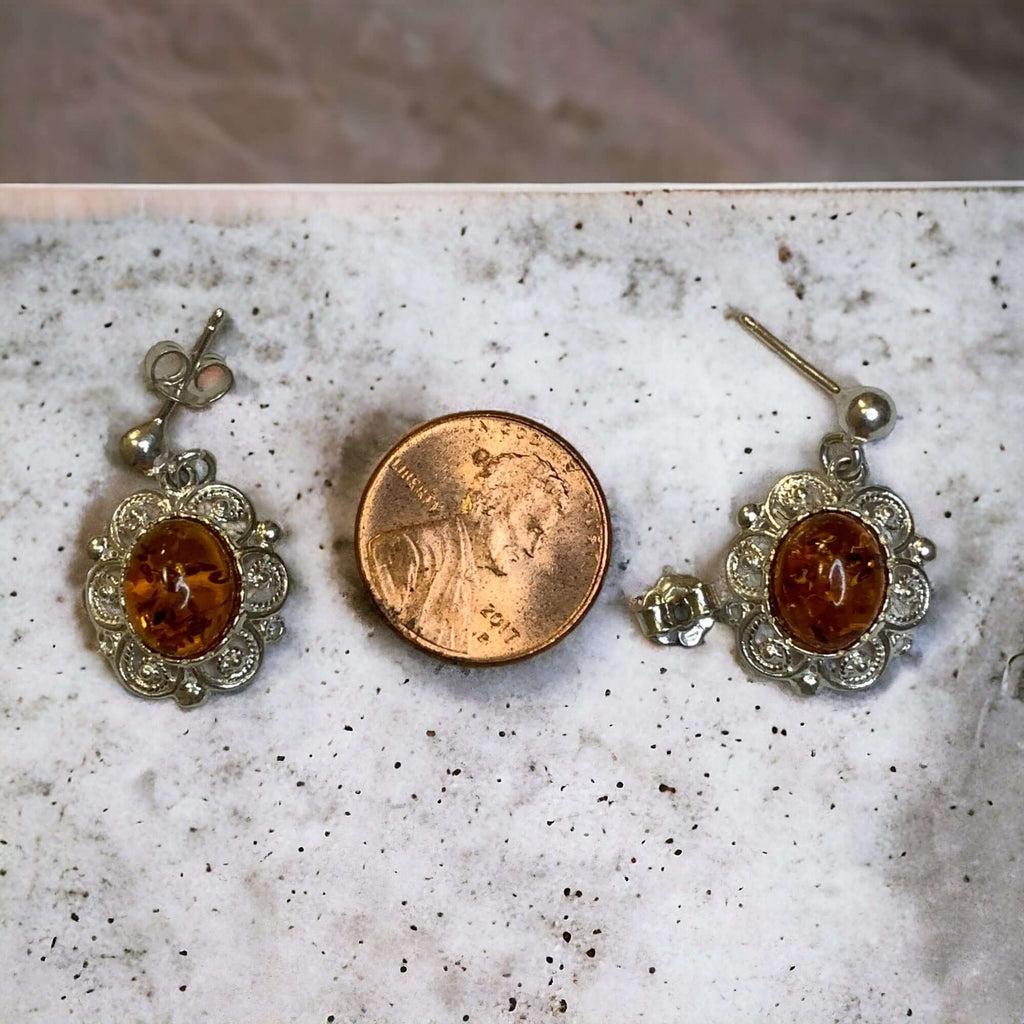 Sterling silver stud drop earrings with cognac amber stones next to a penny for size comparison.