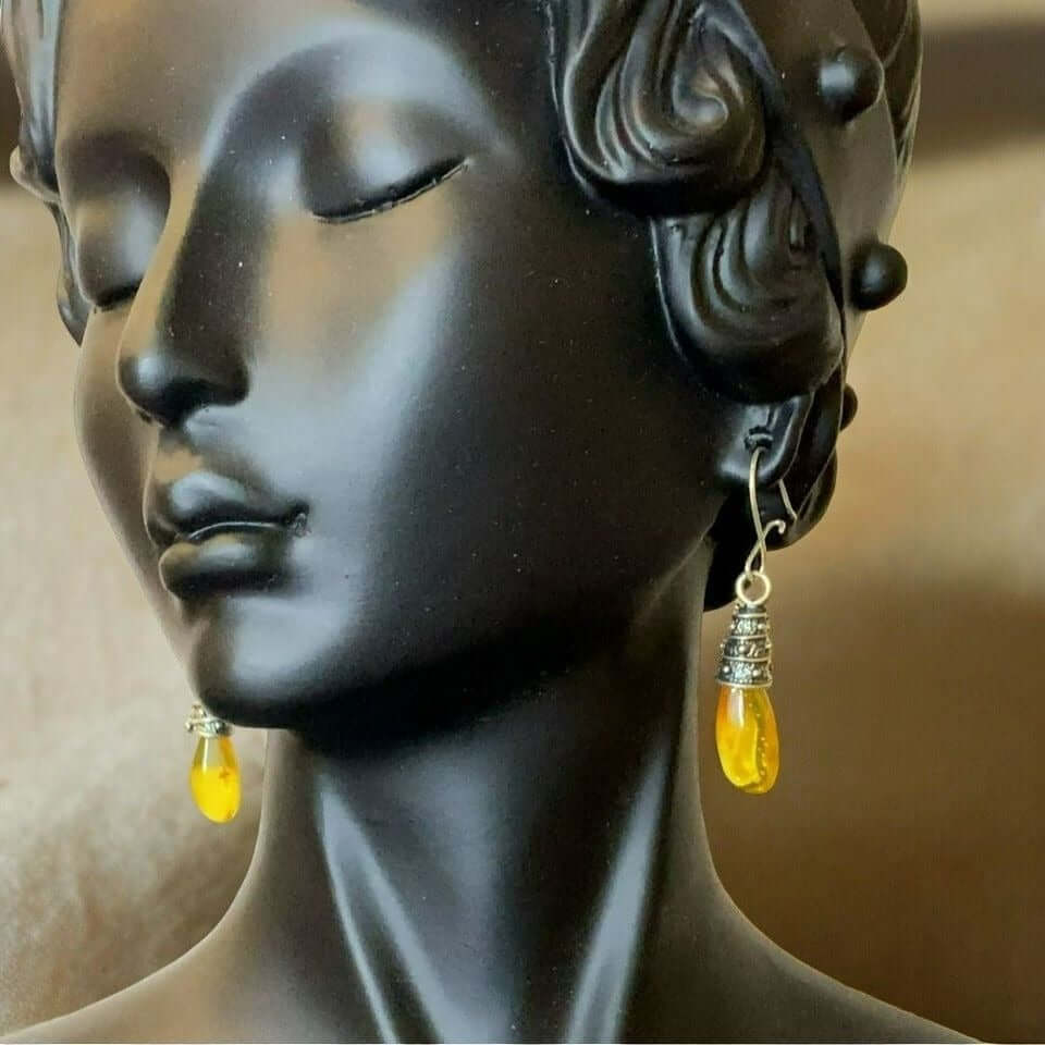 Sterling silver dangle earrings with yellow amber stones displayed on black mannequin bust.