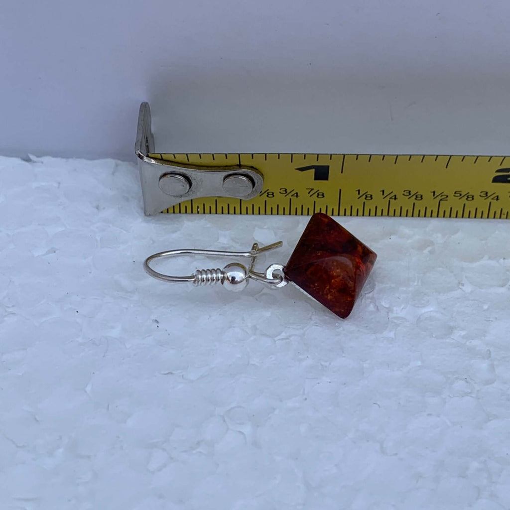 Sterling silver diamond shape Baltic amber drop dangle earring placed next to a ruler on a white surface measuring approximately 1 1/4 inches